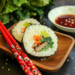 Kimbap auf einer Holzschale mit Stäbchen.